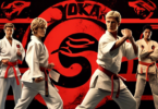 A dynamic scene featuring the main characters from Cobra Kai, wearing their distinctive karate uniforms with the dojo logos, engaged in an intense karate s